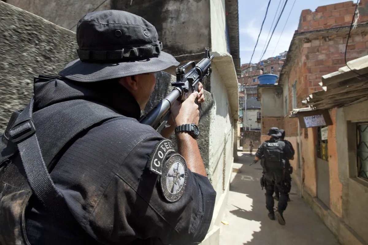 THE WAR CONTINUES: Coordination of special resources policeman covers his comrades as they patrol at Morro do Alemao shantytown in Rio de Janeiro, Brazil, on Nov. 29. Police scoured the sewers under Rio's sprawling slums Monday for hundreds of drug traffickers who fled an unprecedented military onslaught on the favelas (slums) that netted 40 tons of narcotics but few arrests. (Jefferson Bernardes/AFP/Getty Images)
