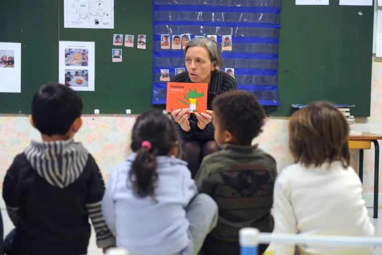 A teacher reads a book to her kindergarten class. An education professor is calling for improved working conditions for teachers, many of whom are leaving the profession due to issues such as overwork and bullying by parents. (Eric Cabanis/AFP/Getty Images)