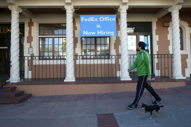 A man passes by a “now hiring” sign outside a FedEx retail store in San Francisco in December. (Justin Sullivan/Getty Images)