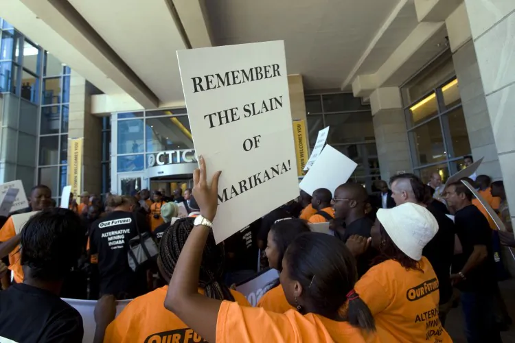 A group of people, holding placards reading “Remember The Slain Of Marikana!” protest outside a mining conference in in Cape Town, South Africa on Feb. 5, 2012. The placard refers to the killing of more than 44 miners in Marikana, South Africa, in August 2012. (Rodger Bosch/AFP/Getty Images)