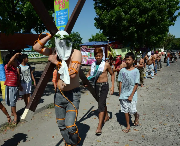 A penitent carries a cross while other flagellate themselves as they participate in symbolic ceremonies which commemorate Jesus Christ's crucifixion and resurrection on Holy Thursday in Angeles City, Pampanga province north of Manila on March 28, 2013. (Ted Aljibe/AFP/Getty Images)