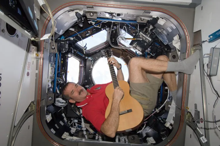 Canadian Space Agency astronaut Chris Hadfield strums his guitar in the International Space Station’s Cupola observatory module on Dec. 25, 2012. Hadfield, a long-time member of an astronaut band called Max Q, later joined with the other five Expedition 34 crew members in a more spacious location to provide an assortment of Christmas carols for the public. (NASA)