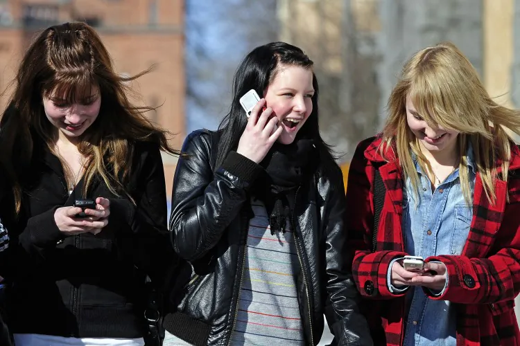 Teenagers are seen using their cell phones after school. (Olivier Morin/AFP/Getty Images)