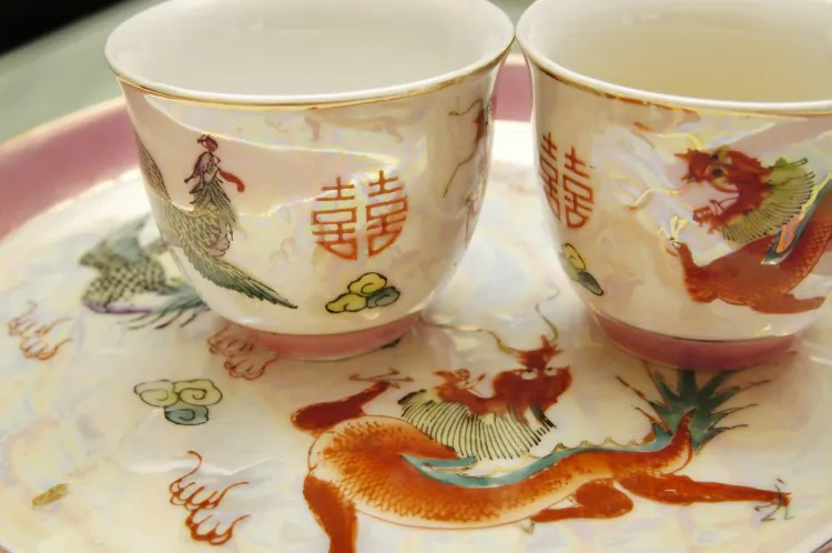 A pair of teacups on a tray at a Chinese wedding display the Chinese double happiness character and the images of the mythical dragon and phoenix to symbolize good luck and a happy and harmonious marriage. (Voon Nam Fook/Photos.com)