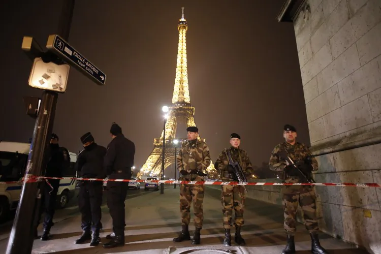 French police officers and soldiers stand guard near the Eiffel Tower in Paris on March 30, 2013. The Eiffel Tower was evacuated in the evening on March 30 after an anonymous caller announced an attack. (Thomas Coex/AFP)