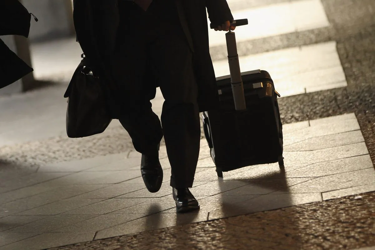 A traveler walks along a street. Creating travel check-lists helps pros pack everything they need on their trip. (Sean Gallup/Getty Images)
