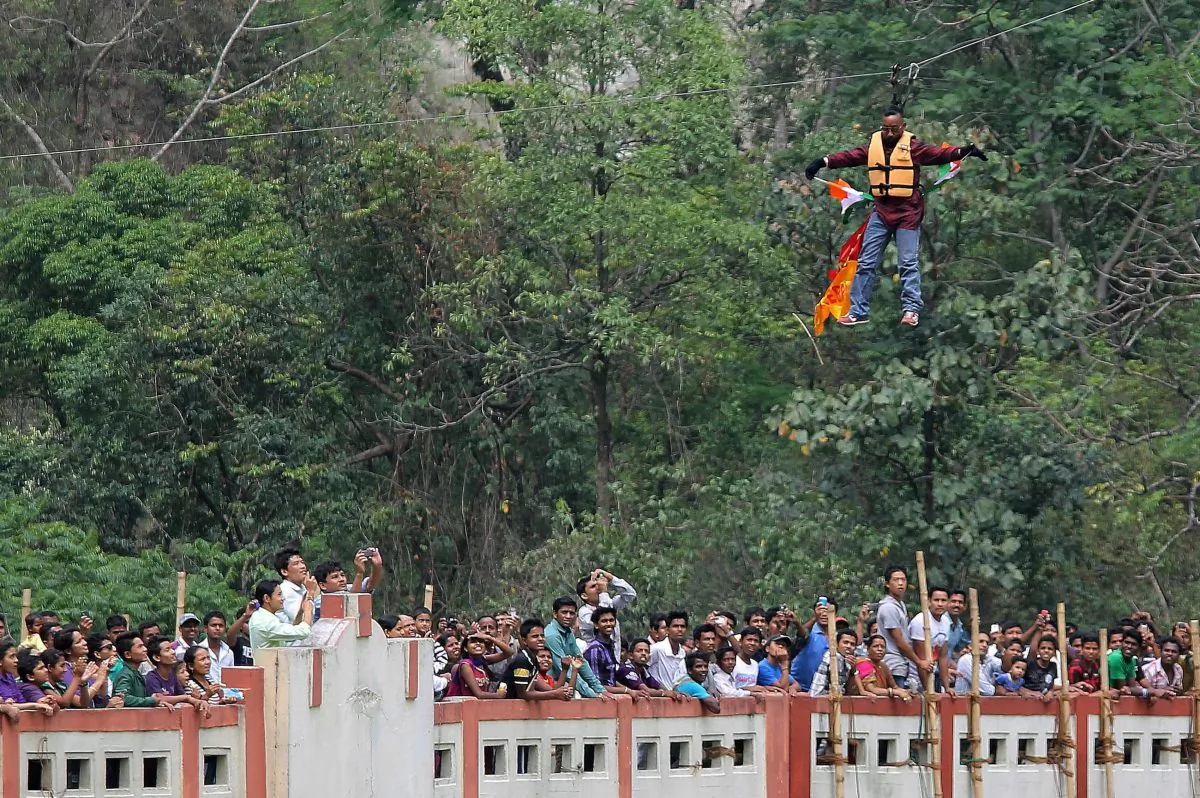 Indian stuntman Sailendra Nath Roy is watched by onlookers as he hangs on a rope while attempting to cross the River Teesta on the outskirts of Siliguri on April 28, 2013. (DIPTENDU DUTTA/AFP/Getty Images)