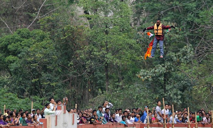 Indian stuntman Sailendra Nath Roy is watched by onlookers as he hangs on a rope while attempting to cross the River Teesta on the outskirts of Siliguri on April 28, 2013. (DIPTENDU DUTTA/AFP/Getty Images)