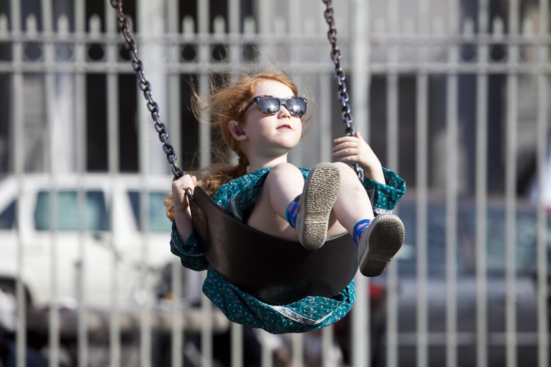 Grace Gibbon, 4, enjoys a swing at the Thompson St. playground in SoHo on Monday. Temperatures reached into the 70s for the first time this spring. (Samira Bouaou/The Epoch Times)