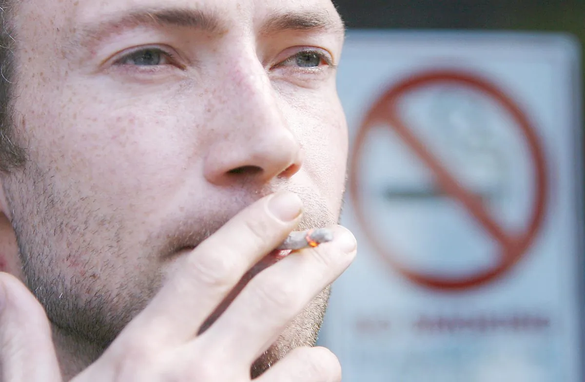 A man smokes a cigarette next to a no smoking sign in a file photo. (Peter Muhly/AFP/Getty Images)