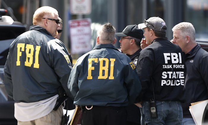 FBI agents gather near the finish line of the Boston Marathon in Boston, on April 16, 2013. Citizens in Boston, and online from around the world, are helping the investigation. (AP Photo/Winslow Townson)