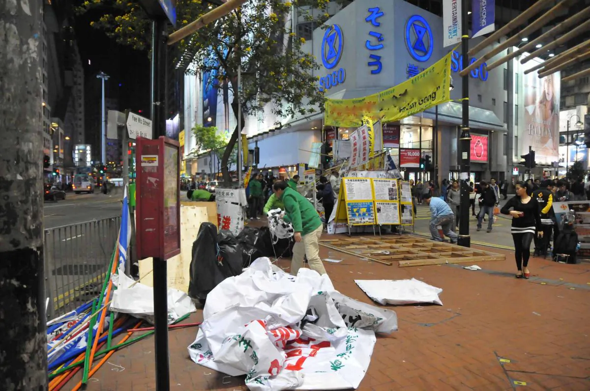 Hong Kong Youth Care Association members take down the banners they had used to obscure the Falun Gong information site outside the popular Sogo department store in Causeway Bay, Hong Kong. The removal of the Youth Care Association banners marks the end of almost 10 months harassment of Falun Gong practitioners by the Chinese Communist Party front group. (Bill Cox/The Epoch Times)