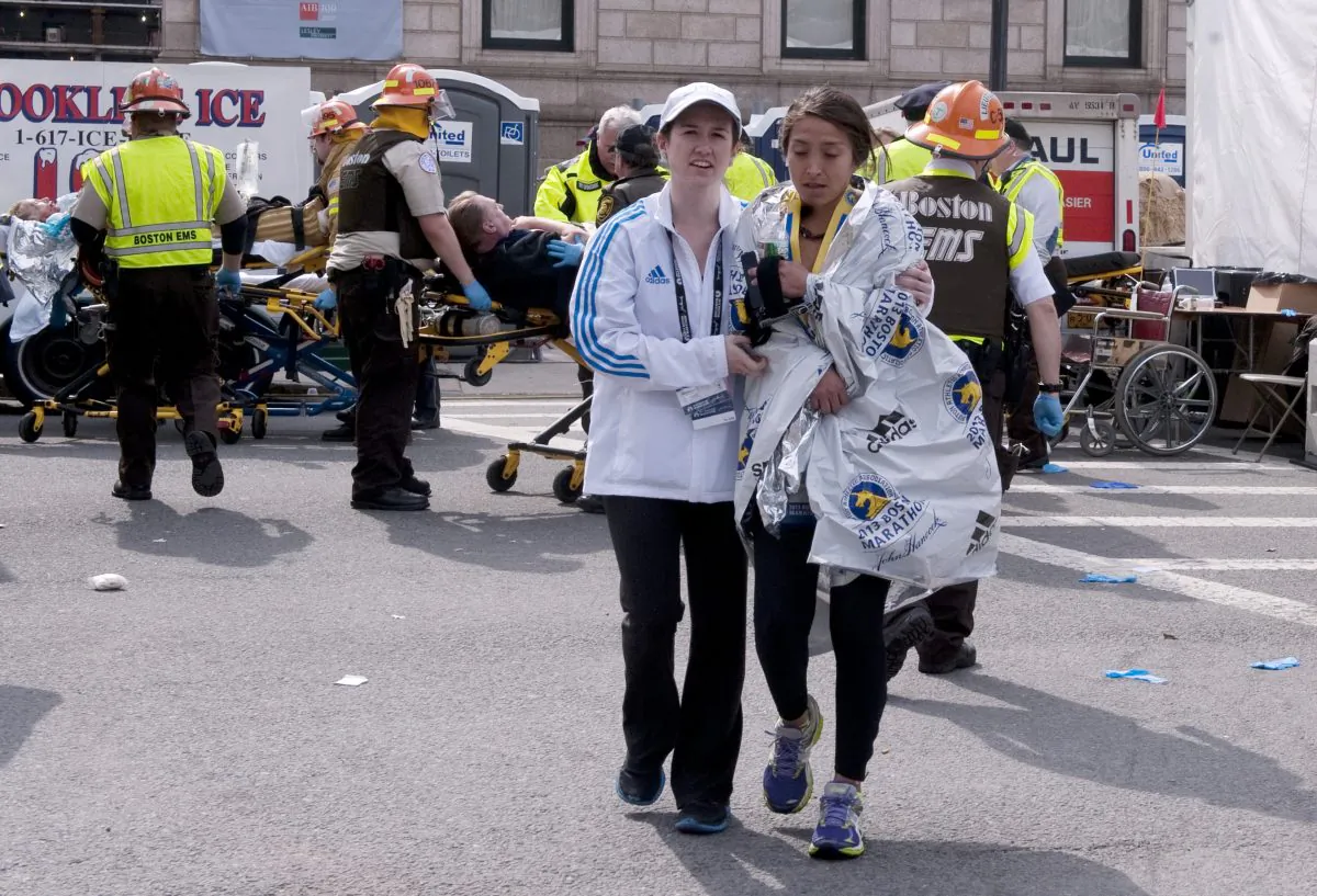 Boston Marathon staff accompany a runner as first responders tend to the injured after the explosions on April 15, 2013. (Xu Ming/The Epoch Times)