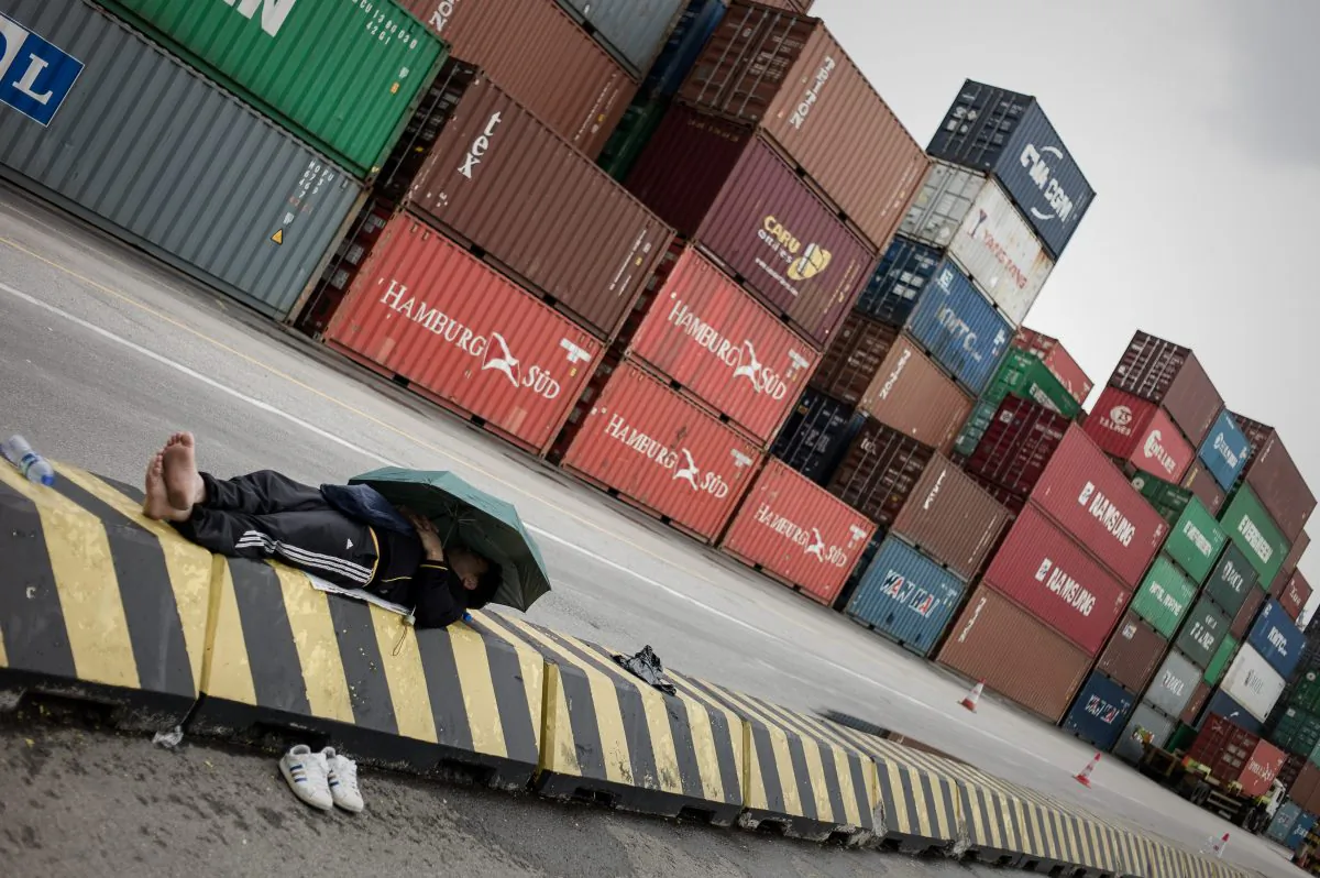 A docker rests in front of containers at the Kwai Chung container terminal in Hong Kong on March 29, 2013. Chinese officials have recently been accused of cooking the books on import and export numbers related to Hong Kong. (Philippe Lopez/AFP/Getty Images)