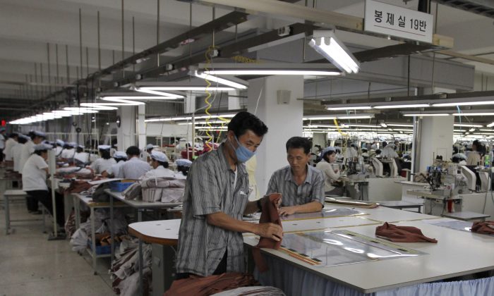 Two North Korean men working for ShinWon, a South Korean clothing maker, prepare garments for production at a factory in Kaesong, North Korea in 2012.  North Korea shut down the Kaesong industrial complex April 8, after weeks of threats and mounting tension. (AP Photo/Jean H. Lee, File)