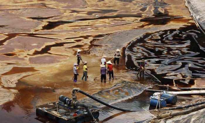 Workers drain away polluted water near the Zijin copper mine in Shanghang on July 13, 2010, after pollution from the mine contaminated the Ting River, a major waterway in southeast China's Fujian Province. Water pollution is a severe environmental problem in China and contributes to high cancer rates. (STR/AFP/Getty Images)