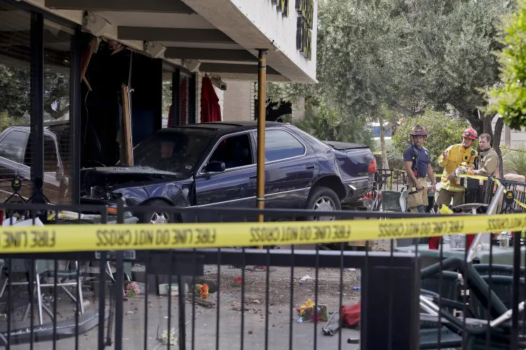 Las Vegas firefighters examine the scene of an accident where a car crashed into a crowded restaurant in Las Vegas on April 1, 2013. Ten people were seriously injured and at least one person was arrested Monday after the car plowed into the patio of the Egg & I restaurant during the lunch hour and came to rest with its hood inside a shattered plate glass window. (AP Photo/Julie Jacobson)