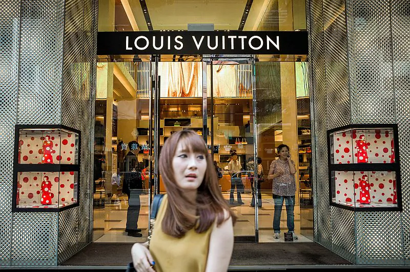 A shopper passes in front of a Louis Vuitton store in Hong Kong, September 2012. (PHILIPPE LOPEZ/AFP/Getty Images)