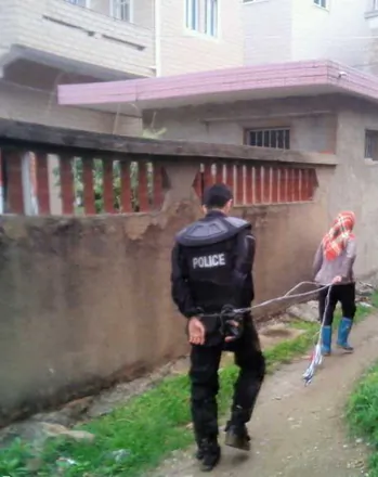 A woman leads a police officer captured after a standoff with authorities over land grabs in Dongwiao Town, Fujian Province, on May 11, 2013. (molihua.org)