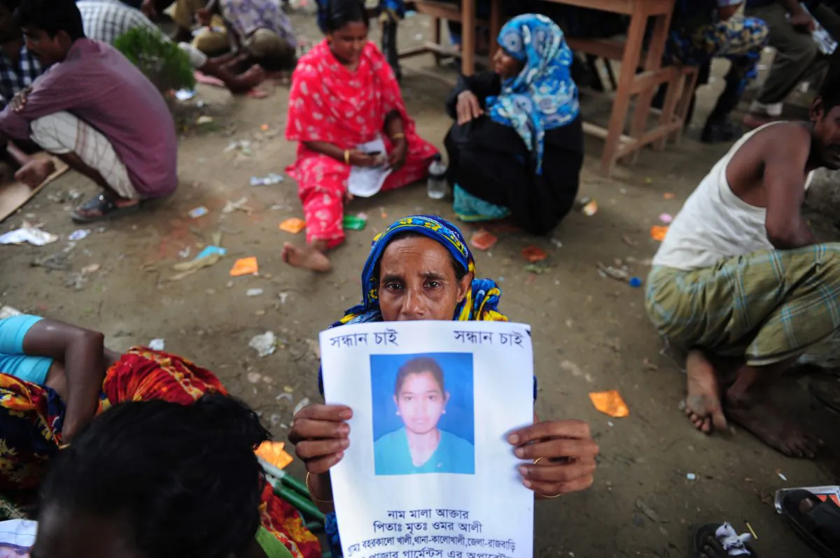  A Bangladeshi family member holds up the portrait of her missing relative, believed to be trapped in the rubble of an eight-story building collapse on the outskirts of Dhaka, on April 29, 2013. After hundreds died, the question arises whether global supply chains are at fault for the building's collapse. (Munir Uz Zaman/AFP/Getty Images)