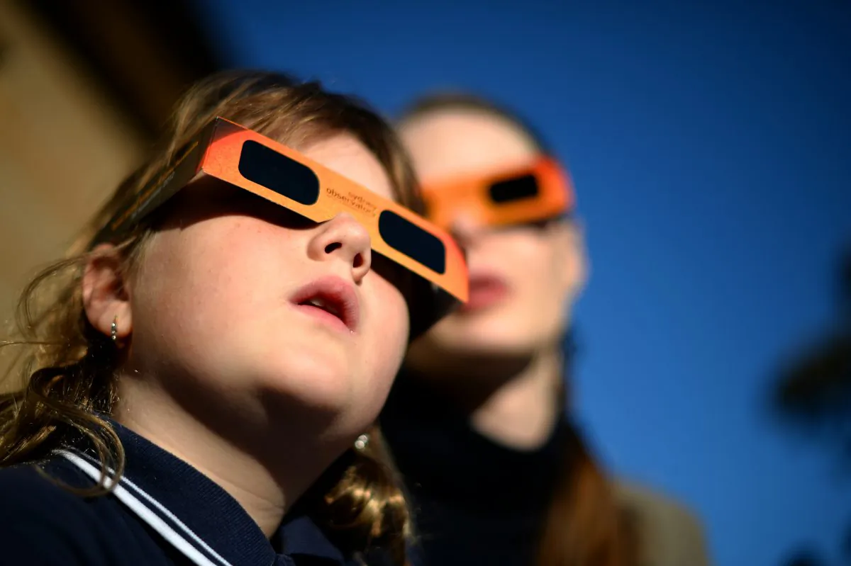 A child watches a partial solar eclipse with a woman at the Sydney Observatory on May 10, 2013. (Saeed Khan/Getty Images)
