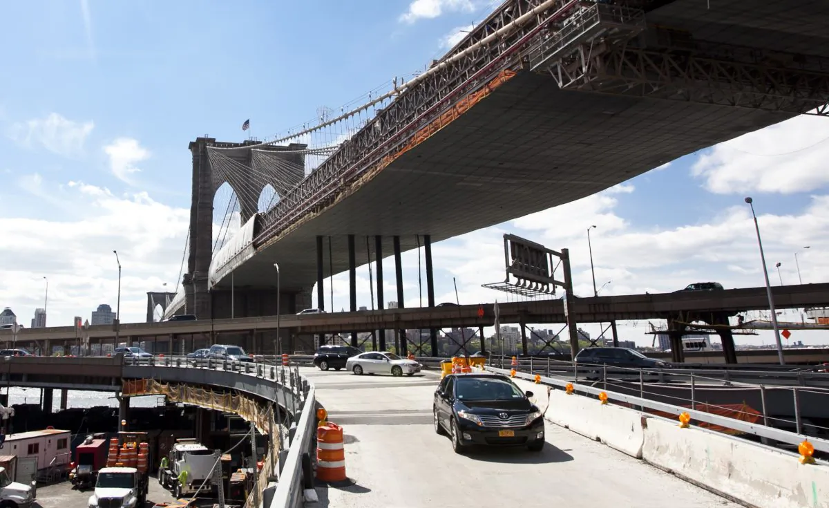 Cars enter the Brooklyn Bridge and Manhattan's Civic Center at a fork on a newly-expanded ramp onto the Brooklyn Bridge. In the background, the Brooklyn Bridge is covered with tarp and scaffolding as it is being repainted. The new ramp and the repainting are part of a $508 million renovation of the Brooklyn Bridge. (Samira Bouaou/Epoch Times)