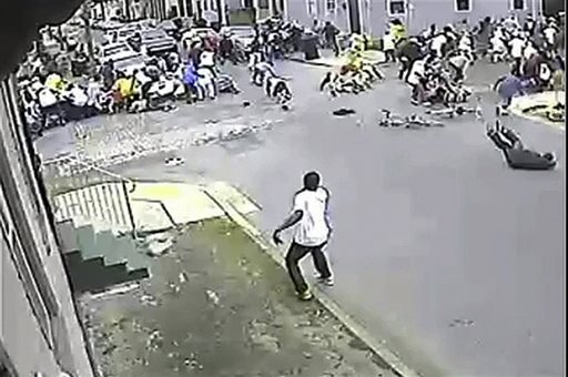 In this image taken from video and provided Monday, May 13, 2013, by the New Orleans Police Department, a possible shooting suspect in a white shirt, bottom center, shoots into a crowd of people, Sunday in New Orleans. Police believe more than one gun was fired in the Mother's Day gunfire that wounded 19 people during a New Orleans neighborhood parade. (AP Photo/New Orleans Police Department)