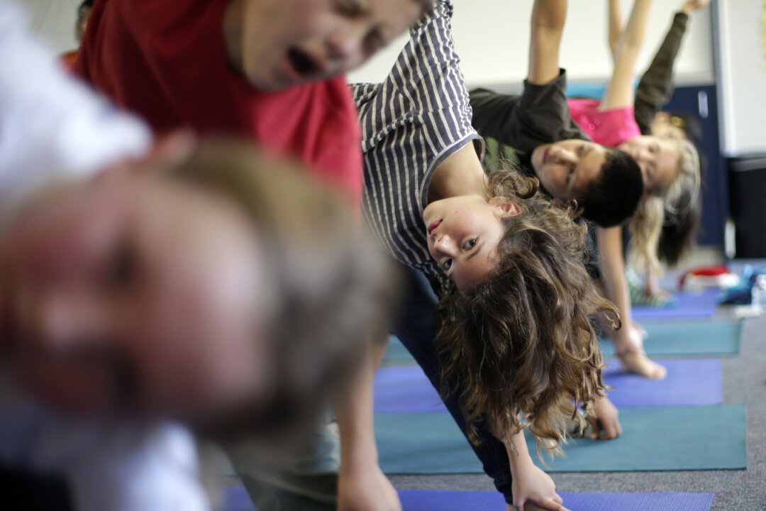 Students hold their position during a yoga class at Capri Elementary School in Encinitas, Calif. in this file photo. Reading, writing, `rithmetic and PE? The prestigious Institute of Medicine is recommending that schools treat physical education as a core subject. At least an hour of vigorous or moderate physical activity every day is recommended. (AP Photo/Gregory Bull, File)