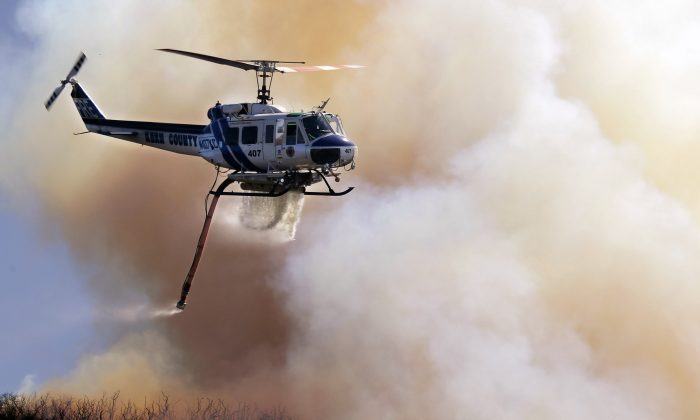 A fire helicopter makes a water drop on a hotspot over a hill near Thousand Oaks, Calif. in this file photo. A wildfire near Santa Barbara caught thousands of campers off-guard and forced their evacuation May 27. (AP Photo/Nick Ut)