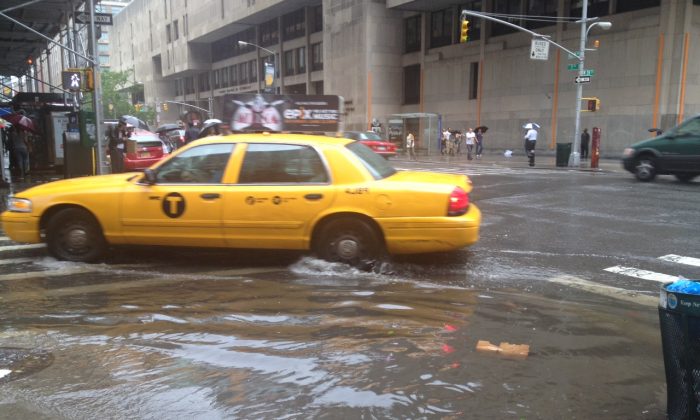 A taxi drives the through the rising water at the corner of 7th Ave and 28th Street in Manhattan at approximately 3:45 p.m. on May 23, 2013 during the heavy rainfall in New York. Flash flood warnings were issued by the National Weather Service until 5:30 p.m. (The Epoch Times)