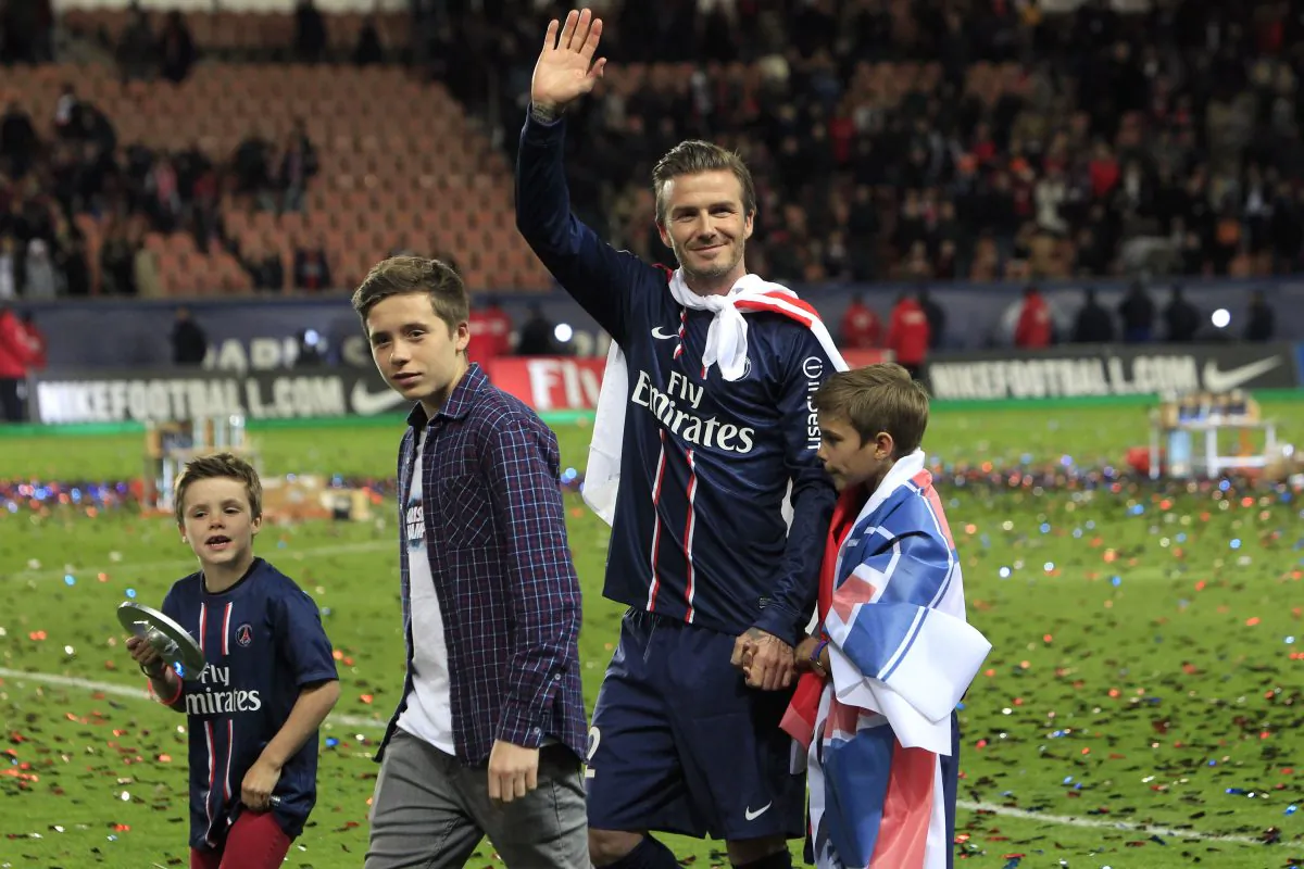 Paris Saint-Germain's midfielder David Beckham from England, center, waves at supporters surrounded by his sons, Brooklyn, second from left, Cruz, left, and Romeo James, right, as he celebrates PSG's French League One title, at the Parc des Princes stadium, in Paris, Saturday, May 18, 2013. (AP Photo/Thibault Camus)