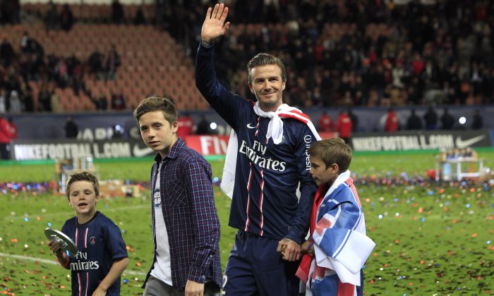 Paris Saint-Germain's midfielder David Beckham from England, center, waves at supporters surrounded by his sons, Brooklyn, second from left, Cruz, left, and Romeo James, right, as he celebrates PSG's French League One title, at the Parc des Princes stadium, in Paris, Saturday, May 18, 2013. (AP Photo/Thibault Camus)