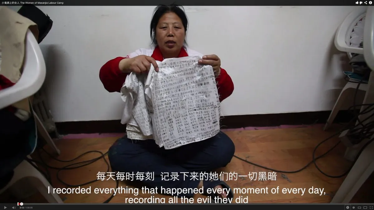 Liu Hua holds up the diaries of torture and abuse that she had smuggled from the labor camp. After saying the line that appears in the subtitle in this picture, she said: "And had the women smuggled it out their vaginas." (Screenshot via The Epoch Times)