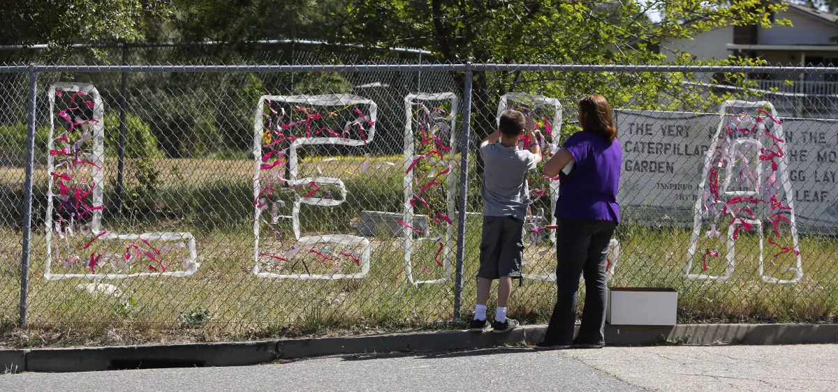 In this April 29, 2013 file photo, teacher Cecilia Richardson helps a student tie a ribbon honoring murder victim, third grader Leila Fowler, at Jenny Lind Elementary School in Valley Springs, Calif. (AP Photo/Rich Pedroncelli, File)