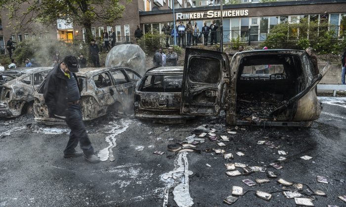 A bystander checks the debris of a burnt out cars in the Stockholm suburb of Rinkeby after youths rioted in several different suburbs around Stockholm, Sweden, for a fourth consecutive night on May 23, 2013. In the suburb of Husby, where the riots began on Sunday in response to the fatal police shooting of a 69-year-old machete-wielding man, 80 percent of residents are immigrants and the unrest has highlighted Sweden's failure to integrate swathes of its immigrant population. (Fredrik Sandberg/AFP/Getty Images) 