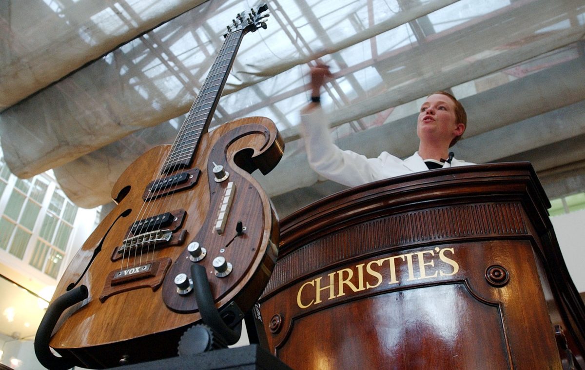A 1966 custom-made VOX Kensington guitar is displayed in front of Helen Bailey a Christie’s auctioneer as she takes bids for other unseen lots during a Pop music memorabilia sale at Christie’s auctioneers in London, Wednesday, May 5, 2004. The guitar sold to a commissioned bidder for 117,250 British pounds, (US$205,188). The guitar will be auctioned off later this month by Julien’s Auctions at the New York City Hard Rock Cafe. (AP Photo/Richard Lewis)