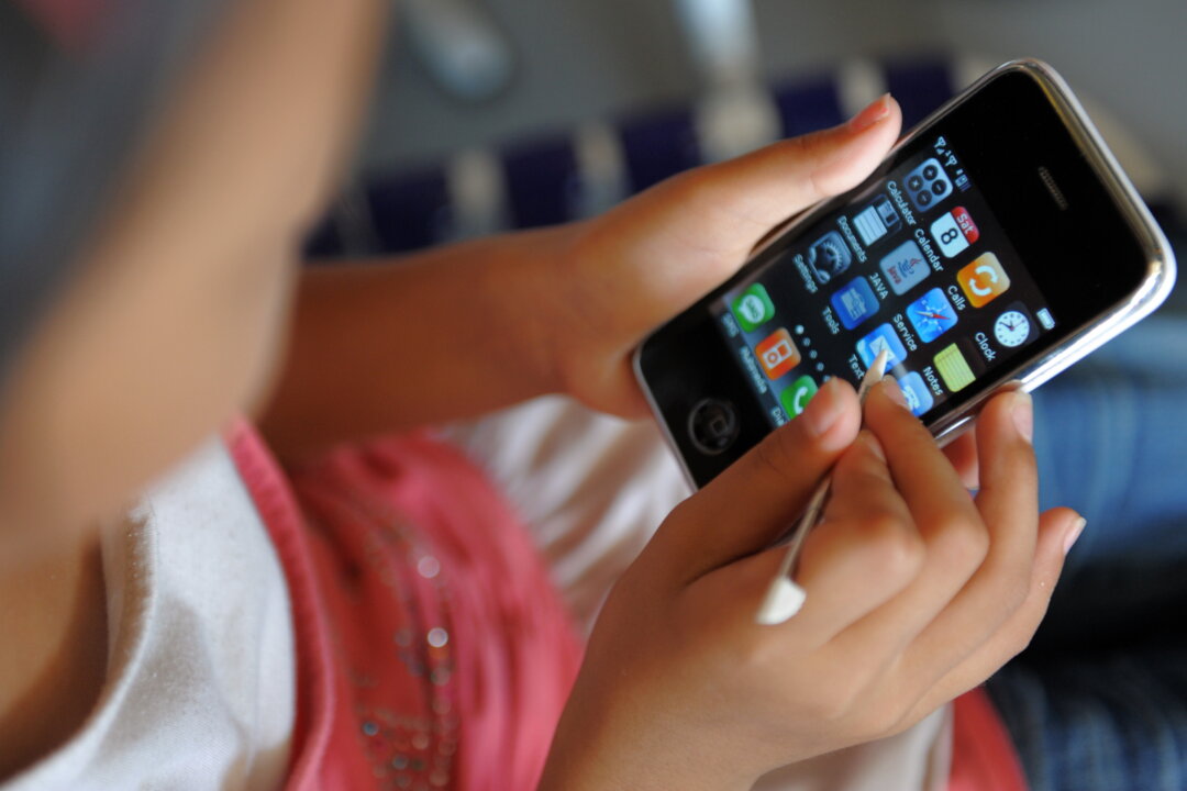 A young girl uses the touch screen of a mobile phone. Public health organizations say that young people should avoid using cellphones, because the electromagnetic radiation wireless devices emit may cause cancer. (Tang Chhin/AFP/Getty Images)