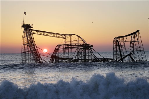 In a Feb. 25, 2013 file photo, the sun rises in Seaside Heights, N.J., behind the Jet Star Roller Coaster which has been sitting in the ocean after part of the Funtown Pier was destroyed during Superstorm Sandy. Work is expected to start Tuesday afternoon, May 14, 2013 to remove the Jet Star coaster from the surf in Seaside Heights. (AP Photo/Mel Evans, File)