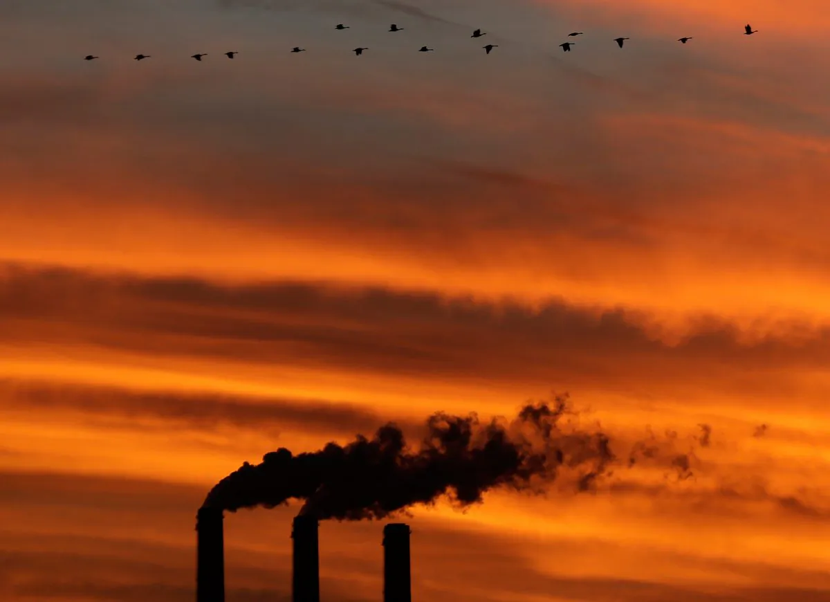 A flock of geese fly past smokestacks at the Jeffrey Energy Center coal power plant near Emmett, Kan, in December 2012. (AP Photo/Charlie Riedel)