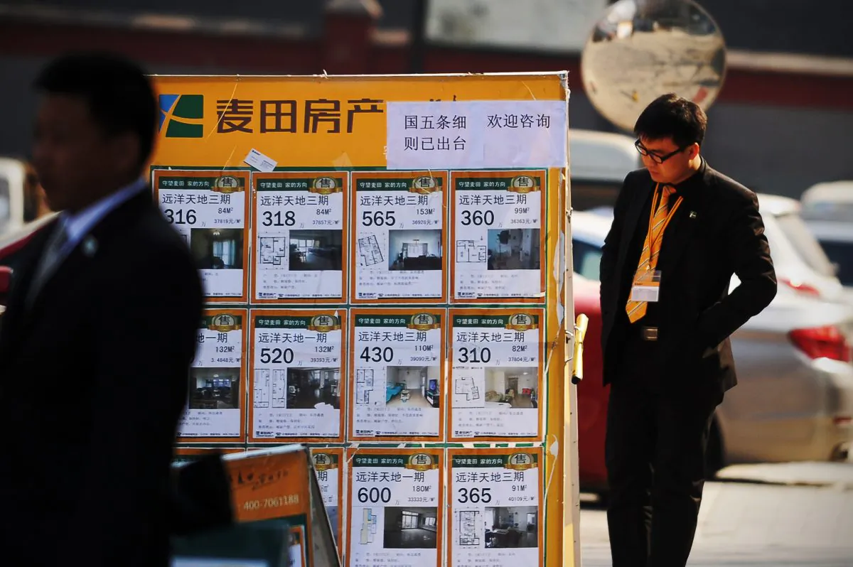 A real estate agent checks a property advertising board in Beijing on April 1, 2013. The rapidly inflating real estate market in major cities has slowed, following new cooling off policies by China’s State Council. (Wang Zhao/AFP/Getty Images)