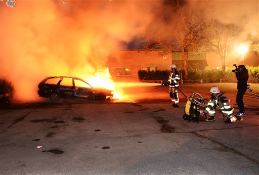 Firemen extinguish a burning car in the Stockholm suburb of Kista after youths rioted in several different suburbs around Stockholm for a third executive night, late May 21, 2013. Some 200 youths hurled rocks at police and set cars ablaze in a suburb of the Swedish capital Stockholm on Tuesday, the second day of rioting triggered by an incident in which police shot and killed a man wielding a knife. (AP Photo/Scanipx Sweden, Fredrik Sandberg)