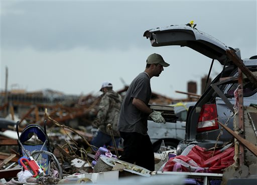 Justin Stehan salvages photographs from his tornado-ravaged home Tuesday, May 21, 2013, in Moore, Okla. A huge tornado roared through the Oklahoma City suburb Monday, flattening entire neighborhoods and destroying an elementary school with a direct blow as children and teachers huddled against winds. The search for survivors and bodies is almost complete, says the city's fire chief. (AP Photo/Charlie Riedel)