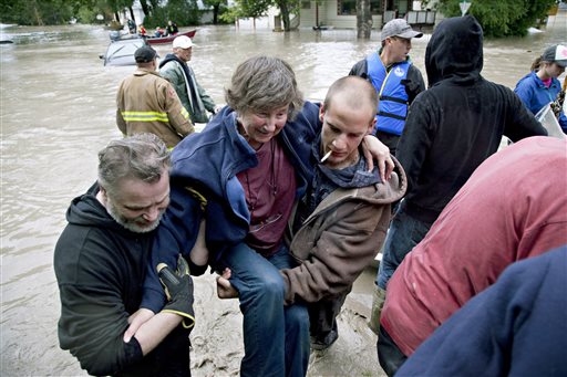 A woman is rescued from the flood waters in High River, Alberta on Thursday, June 20, 2013 after the Highwood River overflowed its banks. Calgary city officials say as many as 100,000 people could be forced from their homes due to heavy flooding in western Canada, while mudslides have forced the closure of the Trans-Canada Highway around the mountain resort towns of Banff and Canmore. (AP Photo/The Canadian Press, Jordan Verlage)