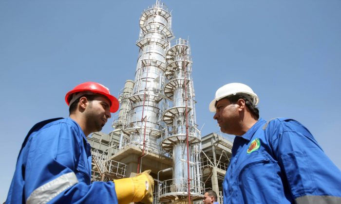 Iraqi workers stand outside the second refinery for crude oil in the Al-Dora refinery complex during its official opening ceremony in Baghdad on Sept. 16, 2010. A boom in oil investment and exports is fueling economic growth attracting foreign companies and capital. (Ahmad Al-Rubaye/AFP/Getty Images)