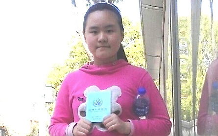Zhang Lin, a democracy activist in China, and his ten-year-old daughter, Anni, have escaped from house arrest in Anhui Province. In this photo, Anni is holding a copy of the Universal Declaration of Human Rights to express her hope that she will be allowed to return to school. (Screenshot from Internet)