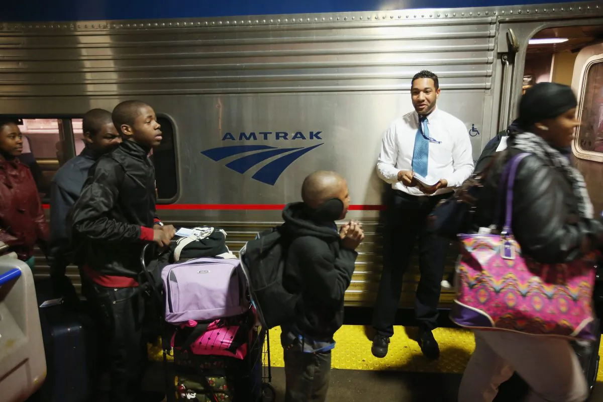 Train attendant Jared Wright helps passengers board Amtrak's Southwest Chief in Union Station bound for Los Angeles on April 9 in Chicago. Train travel is having a revival, with March breaking ridership records for Amtrak. (Scott Olson/Getty Images)