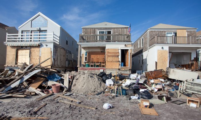 The beachfront home (C) of Bill Guage, a 64-year-old nurse, was slammed with water and sand during Superstorm Sandy. Yet the top floor remains undamaged and livable, and like other homeowners on the Rockaways, Guage plans to continue living in the house. (Amal Chen/The Epoch Times)
