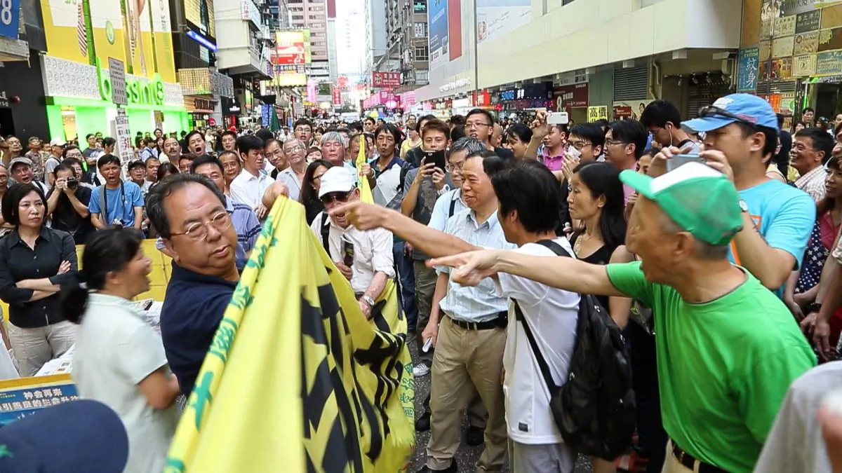 Lam Kwok-on, left, is pointed out by onlookers, after attempting to use his banner to block those belonging to Falun Gong practitioners. The altercation between the Communist Party front group and Falun Gong practitioners is the first major incident since the authorities cracked down on the HCKYCA's banner presence in Hong Kong. (Pan Zaishu/Epoch Times]