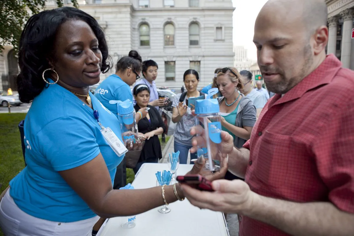 People download the NYC Water app on their phone in exchange for a free water bottle at City Hall Park, June 22. (Samira Bouaou/Epoch Times)