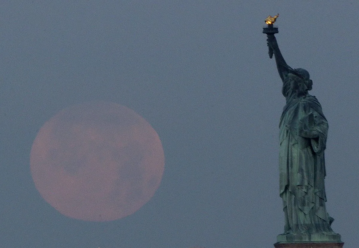A supermoon sets near the Statue of Liberty, Sunday, June 23, 2013, in New York. The larger than normal moon called the "Supermoon" happens only once this year as the moon on its elliptical orbit is at its closest point to earth and is 13.5 percent larger than usual. (AP Photo/Julio Cortez)